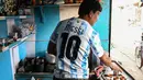 Pemilik warung teh, Shib Shankar Patra sebagai fans timnas Argentina mengenakan jersey saat bekerja di dalam warung tehnya yang dicat dengan warna tim di Ichhapur sekitar 35 km sebelah utara Kolkata pada 12 Desember 2022. Argentina berhasil lolos ke babak semifinal Piala Dunia 2022 Qatar yang akan melawan Kroasia. (AFP/Dibyangshu Sarkar)