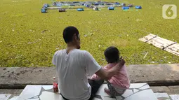 Pengunjung bersantai dekat Setu Sawangan yang tertutup tumbuhan air di Depok, Senin (11/11/2019). Upaya revitalisasi dan normalisasi Setu Sawangan-Bojongsari diharap segera terealisasi agar dapat meningkatkan kunjungan wisatawan dari dalam maupun luar Kota Depok (merdeka.com/Arie Basuki)