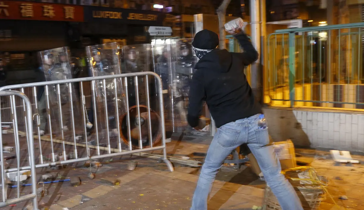 Pengunjuk rasa melemparkan batu ke arah polisi anti huru-hara di Mongkok, Hong Kong, Selasa (9/2). Kerusuhan dimulai ketika pemerintah daerah mencoba untuk menertibkan PKL yang beroperasi. (REUTERS / Bobby Yip)
