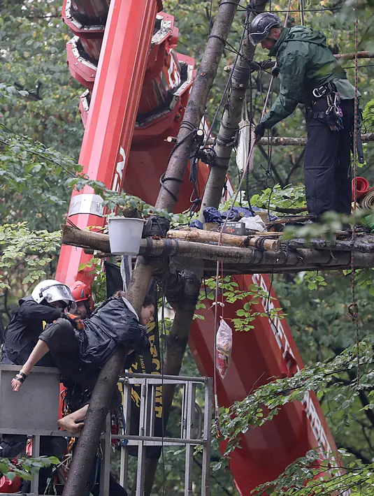 Polisi berusaha menangkap aktivis lingkungan di sebuah rumah pohon di hutan Hambacher Forst, Jerman Barat (13/9). Aktivis tersebut tinggal di rumah pohon untuk  melindungi hutan kuno dari razed untuk tambang batu bara di dekatnya. (Henning Kaiser/dpa/AFP)