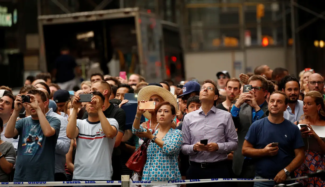 Warga mengabadikan aksi nekat seorang pria yang memanjat gedung Trump Tower di New York, AS, Rabu (10/8). Pria berambut gondrong itu nekat memanjat Menara Trump dengan tali dan cangkir hisap layaknya tengah memanjat tebing. (REUTERS/Carlo Allegri)