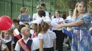 Anak-anak kelas satu mengikuti upacara yang menandai dimulainya kelas di sebuah sekolah di Mariupol, daerah yang dikuasai oleh pasukan separatis yang didukung Rusia, Ukraina timur, Kamis (1/9/2022). Banyak sekolah Ukraina dibuka kembali pada 1 September untuk pertama kalinya sejak invasi Rusia dimulai pada 24 Februari lalu. (AP Photo)