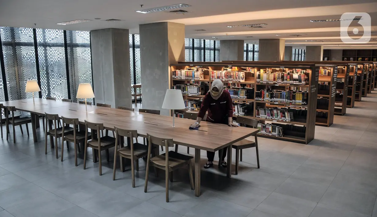 Pekerja membersihkan meja di Perpustakaan Umum Daerah Provinsi DKI Jakarta, Taman Ismail Marzuki, Cikini, Jakarta Pusat, Senin (27/6/2022). Masing-masing lantai di Perpustakaan Umum Daerah Provinsi DKI Jakarta memiliki koleksi literasi sesuai jenis ilmu serta ruangan khusus baca, tempat diskusi, dan arena bermain anak. (merdeka.com/Iqbal S. Nugroho)
