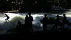 Sejumlah peselancar melihat rekannya menaklukkan ombak buatan saat bermain surfing di sungai 'Eisbach' di taman English Garden di Munich, Jerman (24/6/2019). Sungai Eisbach merupakan salah satu tempat berselancar sungai yang paling populer di Munich. (AP Photo/Matthias Schrader)