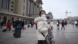 Seorang wanita melihat ke belakang saat dia berjalan ke pintu masuk stasiun kereta api Beijing di ibu kota China (7/1/2023). Ketika migrasi tahunan dimulai dengan orang-orang yang kembali ke kampung halaman mereka untuk perayaan Tahun Baru Imlek. (AFP/Wang Zhao)