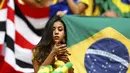 Sambil menunggu dimulainya laga Kamerun vs Brasil di Stadion Nasional Brasil, (23/6/2014), salah satu suporter Selecao terlihat memainkan ponselnya. (REUTERS/Dominic Ebenbichler)