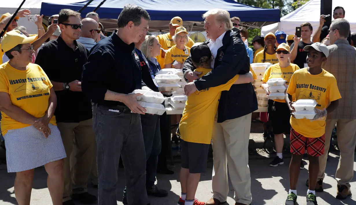 Presiden AS, Donald Trump memeluk seorang anak saat membantu membagikan makanan kepada korban badai Florence di Temple Baptist Church di New Bern, N.C. (19/9). (AP Photo/Evan Vucci)