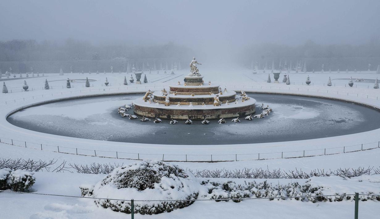 Kota Paris di Prancis berselimut salju tebal, menyusul penurunan suhu ekstrem hingga di bawah 0 derajat Celsius. Tampak dalam foto, salju menyelimuti Kolam Latona dan Parterre di taman Versailles, luar Kota Paris pada Selasa 6 Januari 2026. (GEOFFROY VAN DER HASSELT/AFP)