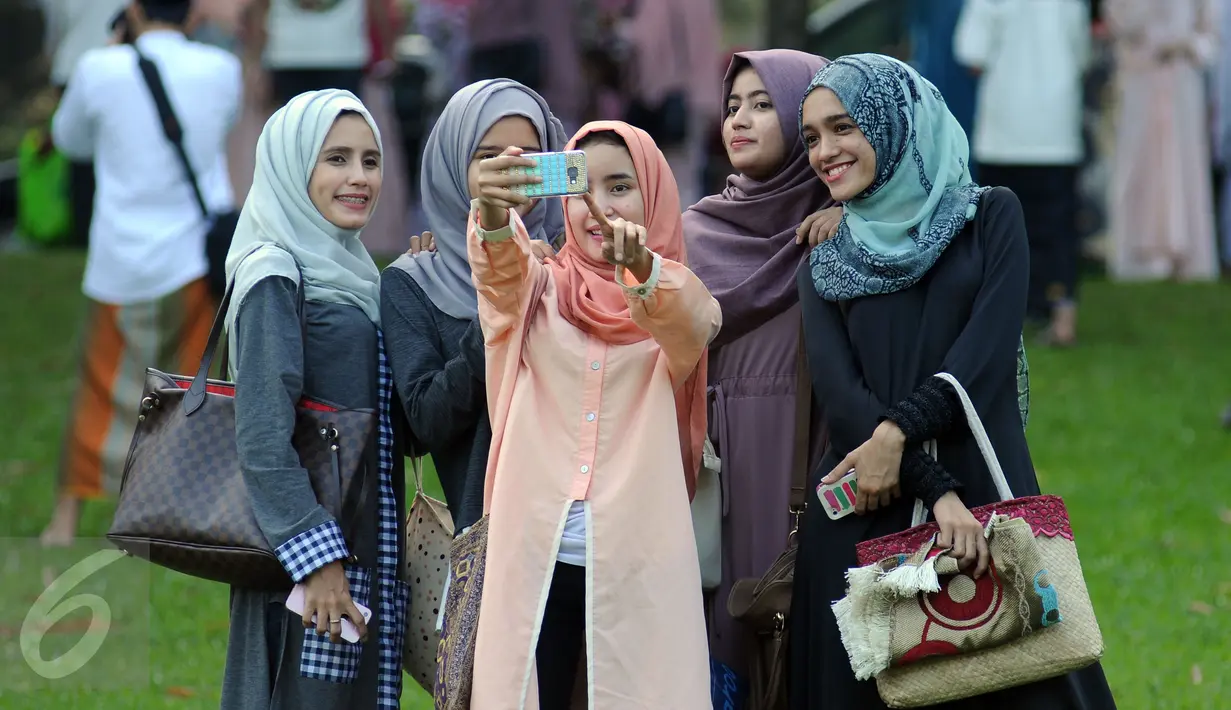 Warga berfoto selfie usai melaksanakan Salat Idul Fitri 1437 H di Kebun Raya Bogor, Rabu (6/7). Pemerintah Kota Bogor menyelenggarakan Salat Idul Fitri 1437 H yang dipusatkan di areal Kebun Raya. (Liputan6.com/Helmi Fithriansyah) 