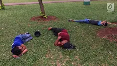 Sejumlah pengunjung bersantai sambil tiduran di sekitar Taman Monas, Jakarta, Rabu (17/1). Dibukanya pagar pembatas Taman Monas membuat warga bisa masuk ke area taman yang mengelilingi lokasi wisata di Ibu Kota tersebut. (Liputan6.com/Immanuel Antonius)