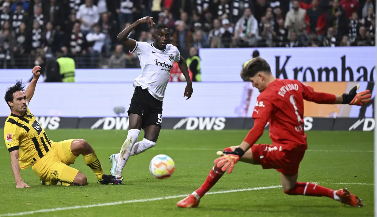 <p>Kiper dan bek Borussia Dortmund, Gregor Kobel dan Mats Hummels mencegah gol penyerang Eintracht Frankfurt, Randal Kolo Muani pada laga pekan ke-12 Bundesliga Jerman 2022/2023 di Deutsche Bank Park, Minggu (30/10/2022) dini hari WIB. Borussia Dortmund memanaskan persaingan di papan atas Bundesliga. (Arne Dedert/dpa via AP)</p>