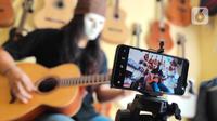 Pemilik showroom dan bengkel Gitar "music666", Ridwan dan Rudi mendemonstrasikan gitar yang akan dijual secara daring di Ciledug, Tangerang, Rabu (22/7/2020). Pemerintah menargetkan 10 juta usaha mikro kecil menengah (UMKM) pada tahun ini terhubung dengan platform digital (Liputan6.com/Angga Yuniar)