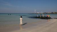 Wisatawan bermain di pantai Woljeongri di pulau Jeju, Korea Selatan (11/5/2019). Topografi Pulau Jeju terbentuk sekitar 2 juta tahun lalu oleh aktivitas vulkanis. Di tengah-tengah pulau muncul Hallasan (Gunung Halla), gunung tertinggi di seluruh Korea (1.950 m). (AFP Photo/Ed Jones)