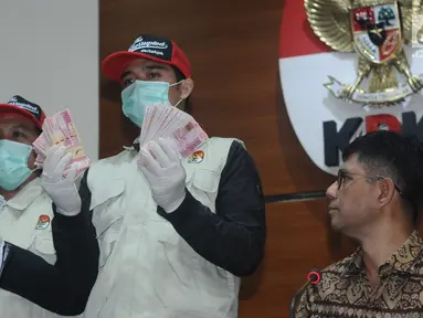 Petugas KPK menunjukkan barang bukti hasil operasi tangkap tangan terhadap Bupati Jombang, Nyono Suharli Wihandoko di Gedung KPK, Jakarta, Minggu (4/2). KPK menyita uang Rp 25,5 Juta dan 9.500 US Dollar. (Liputan6.com/Helmi Fithriansyah)