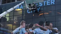 Pekerja memasang poster raksasa bergambar pemain Manchester City terpasang di Stadion Etihad, Manchester, Senin (17/4/2018). Persiapan ini dilakukan untuk merayakan pesta juara Manchester City meraih gelar Premier League. (AFP/Paul Ellis)