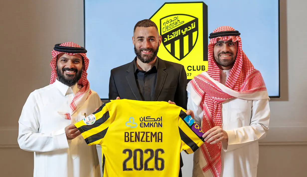 Penyerang asal Prancis, Karim Benzema memegang kaus klub Al-Ittihad Arab Saudi saat ia berpose untuk foto diapit oleh anggota Al-Ittihad, di Madrid pada 6 Juni 2023. (AFP/Liga Pro Saudi/jorge ferrari)