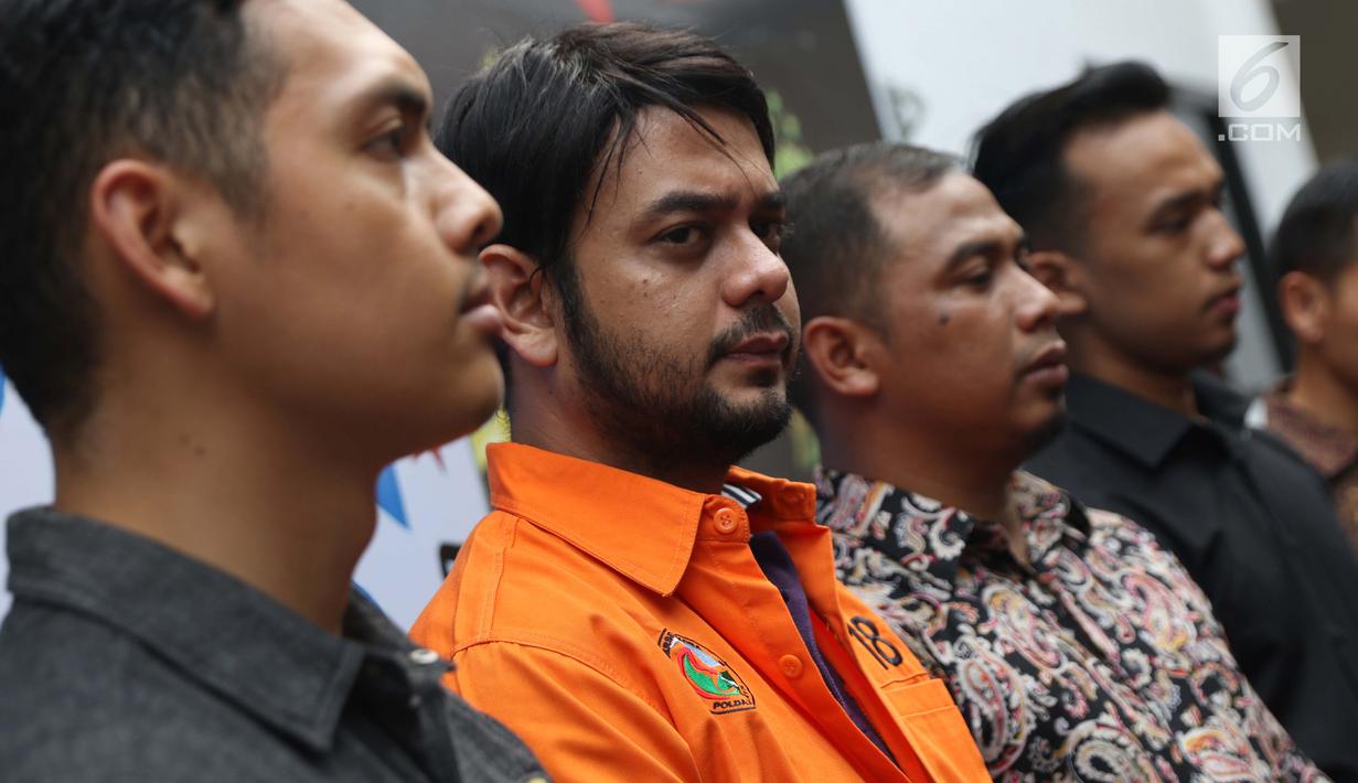 Pesinetron Rio Reifan diapit petugas Direktorat Reserse Narkoba Polda Metro Jaya saat rilis, Jakarta, Jumat (16/8/2019). Rio Reifan kembali ditahan polisi terkait kasus narkoba untuk kali ketiga. (Liputan6.com/Helmi Fithriansyah)