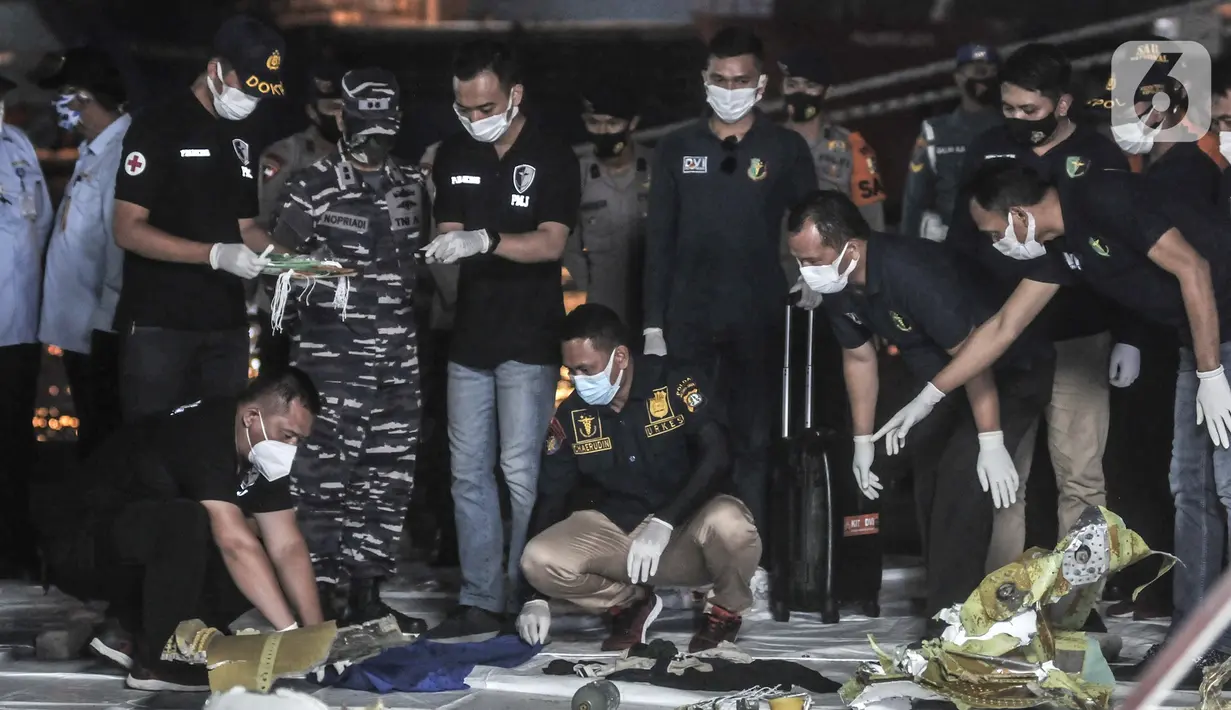 Tim DVI Polri mengidentifikasi pakaian dan bagian tubuh korban kecelakaan Sriwijaya Air SJ 182 yang baru ditemukan tim SAR gabungan di Dermaga JICT 2, Tanjung Priok, Jakarta, Minggu (10/1/2021). Pencarian Sriwijaya Air SJ 182 tetap dilakukan pada malam hari. (merdeka.com/Iqbal S. Nugroho)