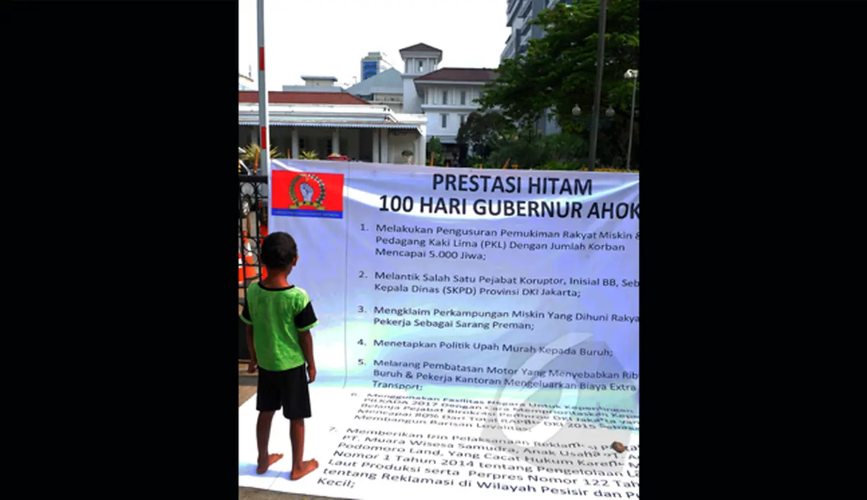 Seorang bocah berdiri di atas spanduk yang berisi tentang prestasi hitam Gubernur Ahok, Balaikota, Jakarta, Jumat (27/2/2015). Mereka menilai Gubernur Ahok gagal menjalankan pemerintahan dalam 100 hari (Liputan6.com/Faisal R Syam)