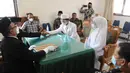 Pengantin pria menggunakan masker mengucapkan kalimat ijab-kabul saat prosesi pernikahan di KUA Pamulang, Tangerang Selatan, Selasa (22/2/2022). Sebanyak 10 pasangan menjalankan akad nikah di KUA Pamulang pada hari ini yang dianggap memiliki tanggal cantik. (merdeka.com/Arie Basuki)