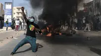 Seorang pendukung oposisi bereaksi di depan barikade yang terbakar selama demonstrasi yang diserukan oleh partai-partai oposisi di Dakar pada 4 Februari 2024. (Seyllou/AFP)