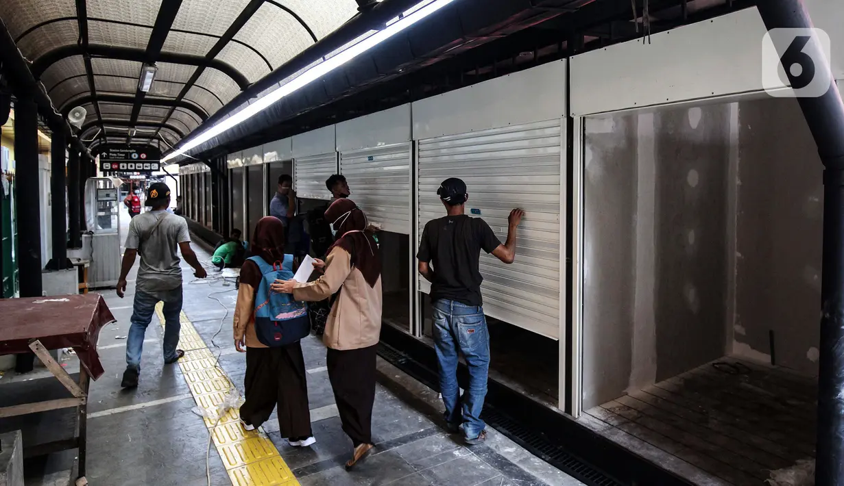 Warga melintas saat pekerja menyelesaikan pembuatan ruko untuk UMKM di stasiun Gondangdia, Jakarta, Sabtu (16/10/2021). Penataan stasiun ini merupakan kerja sama antara Pemprov DKI Jakarta dan PT KCI guna menghadirkan sarana transportasi yang terintegrasi. (Liputan6.com/Johan Tallo)
