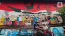 Warga duduk dengan latar belakang mural berbagai pakaian adat Indonesia di Kampung Pancasila, Karang Tengah, Kota Tangerang, Selasa (1/6/2021). Sejumlah kegiatan diadakan warga, Komunitas Taman Potret dan TNI ini untuk memperingati Hari kelahiran Pancasila. (Liputan6.com/Angga Yuniar)