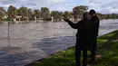 Orang-orang melihat daerah banjir di pinggiran Kota Melbourne, Maribyrnong, Australia, Jumat (14/10/2022). Banjir pun dikhawatirkan berlangsung hingga akhir pekan ini. (William WEST/AFP)