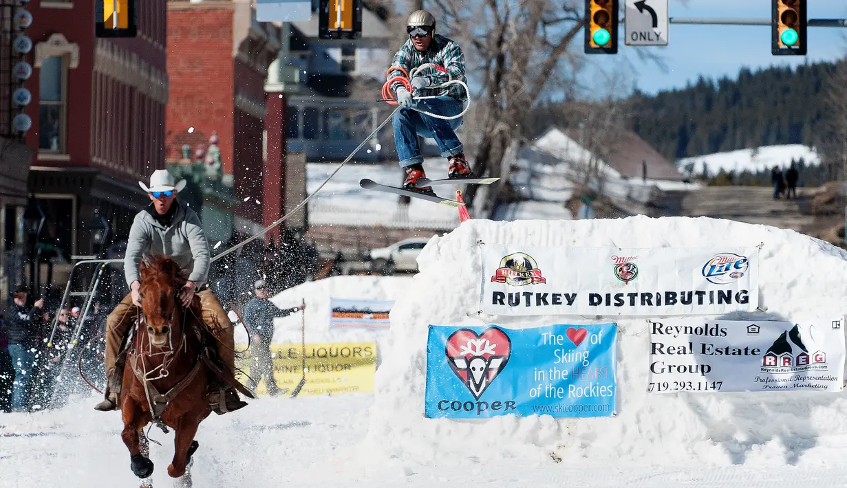 Joki yang bernama Zach West menarik pemain ski salju Greg Dahl yang melompat saat mengikuti kompetisi Leadville Ski Joring ke-70 di Leadville, Colorado (4/3). (AFP Photo/Jason Connolly)