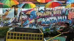 Warga melintasi gambar mural/grafiti di Kampung Bekelir, Jalan Perintis Kemerdekaan, Kota Tangerang, Banten, Selasa (17/4). Kampung Bekelir pada 10 tahun lalu merupakan kawasan yang kumuh. (Merdeka.com/Arie Basuki)