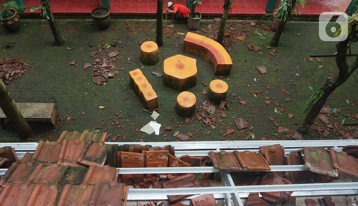 Pekerja membersihkan reruntuhan genting yang memenuhi halaman sekolah akibat gempa di SMK Negeri 1 Turen, Malang, Jawa Timur, Minggu (11/4/2021). Gempa yang mengguncang kawasan Malang dan sekitarnya membuat sejumlah bangunan rusak. (merdeka.com/Nanda F. Ibrahim)