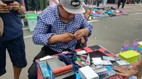 Aksi Sugeng memperbaiki kartu yang rusak di CFD Bundaran HI, Jakarta Pusat, Minggu (31/3/2019). (Liputan6.com/Ika Defianti)