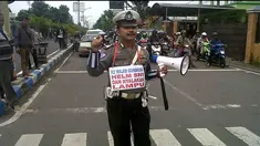 Salah seorang anggota polisi lalu lintas Polres Bangkalan, Madura, Jawa Timur Bripka Komang melakukan aksi lucu dan unik di Traffic Light Junok.Ia menggunakan kalung terbuat dari kertas yang bertuliskan “Khusus Roda Dua, Wajib Nyalakan Lampu Utama ...