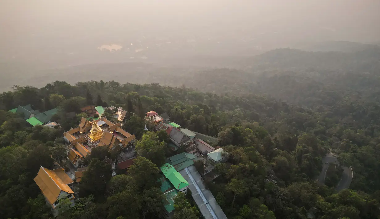 Foto udara yang diambil pada 11 April 2023 ini menunjukkan kuil Buddha Doi Suthep di depan polusi berat yang melanda kota Chiang Mai. (AFP/Lillian Suwanrumpha)