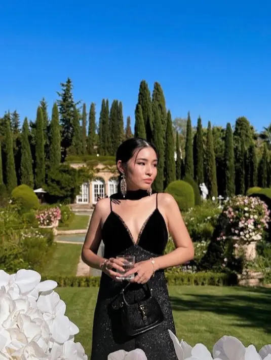 Wajahnya dipoles dengan riasan flawless mengaplikasikan lipstik nude. Rambut panjang hitam diikat ke belakang dengan bagian depan belah dua rapi. [@tiffanysoetanto]