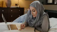 Ilustrasi muslimah, belajar, hadis. (Foto oleh cottonbro studio: https://www.pexels.com/id-id/foto/woman-in-grey-hijab-menggunakan-macbook-air-4626338/)
