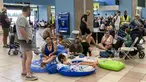 Para turis menunggu di aula keberangkatan bandara saat evakuasi sedang berlangsung akibat kebakaran hutan, di pulau Rhodes, Yunani, Minggu (23/7/2023). (Will VASSILOPOULOS / AFP)
