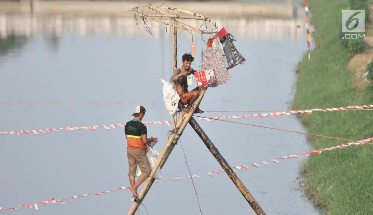 Peserta menurunkan sejumlah hadiah dari puncak pinang saat lomba panjat pinang dalam rangka HUT ke-74 RI di Kanal Banjir Timur, Jakarta, Sabtu (17/8/2019). (merdeka.com/Iqbal S. Nugroho)