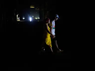 Orang-orang menyeberang jalan saat pemadaman listrik di Havana, Kuba, Rabu 4 Maret 2026. Pemadaman listrik besar melanda dua pertiga wilayah Kuba, termasuk ibu kota Havana. (AP Photo/Ramon Espinosa)
