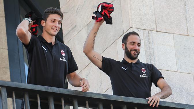 Pemain baru AC Milan, Gonzalo Higuain dan Mattia Caldara melempar jersey ke suporter dari balkon di alun-alun pusat Milan Piazza Duomo (3/8). Caldara didapatkan secara permanen dan menandatangani kontrak sampai 30 Juni 2023. (AFP Photo/Stringer)