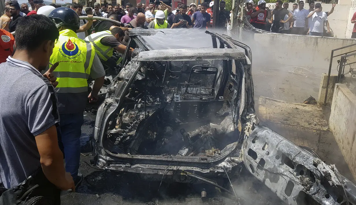 Pekerja Pertahanan Sipil memeriksa sisa-sisa mobil yang terbakar yang dilaporkan menjadi sasaran serangan pesawat tak berawak atau drone Israel di kota pelabuhan selatan Sidon, Lebanon, Senin (26/8/2024). (AP Photo/Mohammed Zaatari)