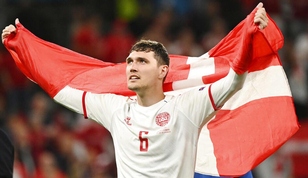 Pemain Timnas Denmark, Andreas Christensen, melakukan selebrasi dengan mengibarkan bendera nasional. Denmark jadi tim pertama dalam sejarah Piala Eropa yang lolos ke babak knockout setelah kalah di dua laga pertamanya di fase grup. (Jonathan Nackstrand/Pool via AP)