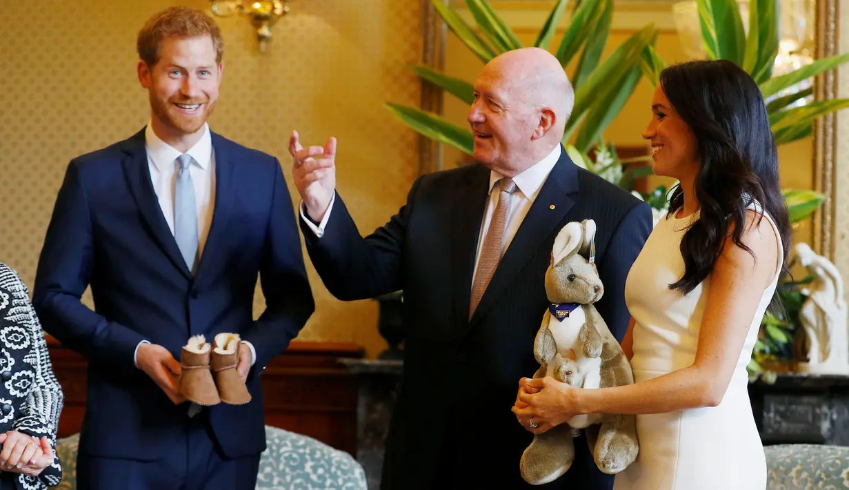 Pangeran Harry dan Meghan Markle menerima hadiah Gubernur Jenderal Australia Sir Peter Cosgrove dalam kunjungan resmi di Sydney, Selasa (16/10). Meghan Markle yang sedang hamil muda tampak senang menerima hadiah bayi pertamanya (Phil Noble/Pool via AP)
