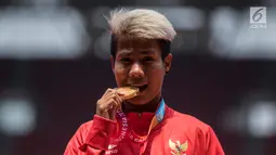 Atlet lompat jauh Indonesia, Rica Oktavia menggigit medali emas Asian Para Games 2018 di SUGBK, Jakarta, Senin (8/10). Rica menorehkan lompatan mencapai 5,25 meter. (Bola.com/Vitalis Yogi Trisna)