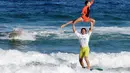 Olah tubuh atlet Prancis, Clement Cetran dan Dhelia Birou Cetran, saat beraksi dalam Kejuaraan Internasional Surfing Tandem di Biscarrosse, Prancis, (23/7/2016). (AFP/Mehdi Fedouach)