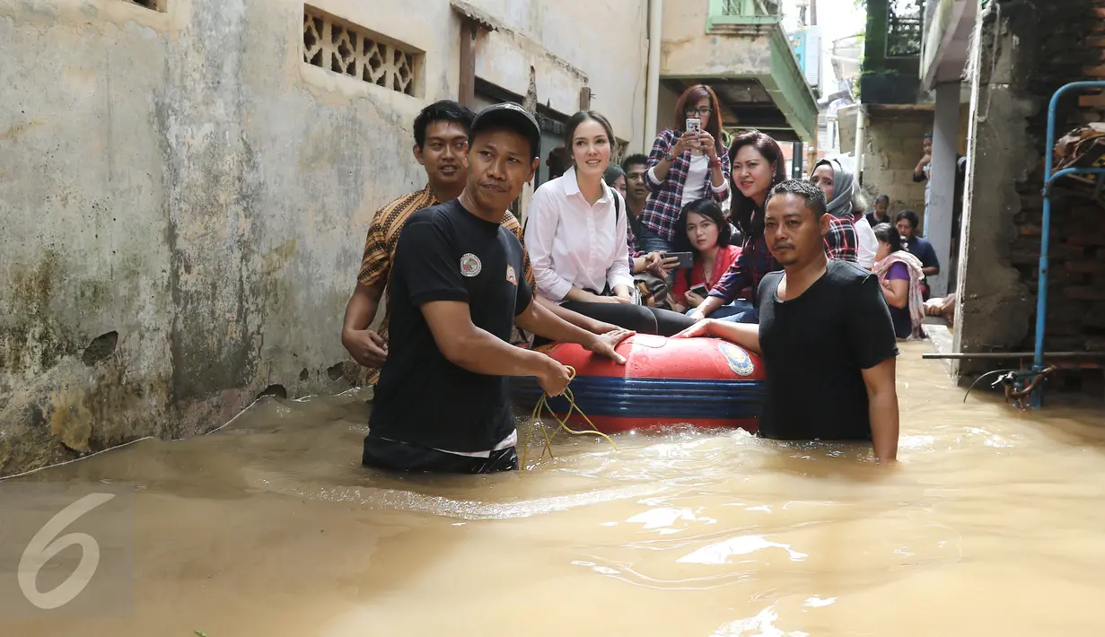 Aktris Cathy Sharon bersama istri wakil gubernur DKI Jakarta Heppy Farida djarot menaiki perahu karet meninjau lokasi banjir di jalan Bina Warga, Pancoran, Jakarta Selatan, Selasa (21/02). (Liputan6.com/Herman Zakharia)