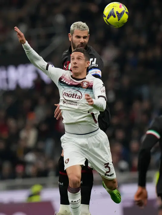 Pemain AC Milan Theo Hernandez (atas) berebut bola dengan pemain Salernitana Domagoj Bradaric pada pertandingan sepak bola Serie A Liga Italia di Stadion San Siro, Milan, Italia, 13 Maret 2023. Pertandingan berakhir imbang dengan skor 1-1. (AP Photo/Luca Bruno)