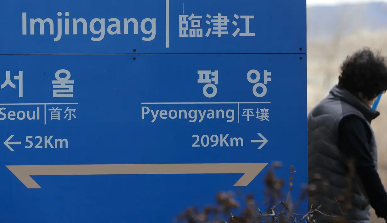 Seorang wanita berjalan melalui sebuah papan nama yang menunjukkan jarak ke Ibu Kota Korea Utara Pyongyang dan Ibu Kota Korea Selatan Seoul dari Stasiun Imjingang di Paju, Korea Selatan, Senin (5/3). (AP Photo/Lee Jin-man)