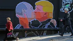 Warga melewati mural bergambar calon Presiden AS, Donald Trump dan Presiden Rusia, Vladimir Putin sedang berciuman di Vilnius, (13/5). Mural ini dibuat sebagai sindiran terhadap Donald Trump dan Vladimir Putin. (AFP PHOTO/Petras Malukas)