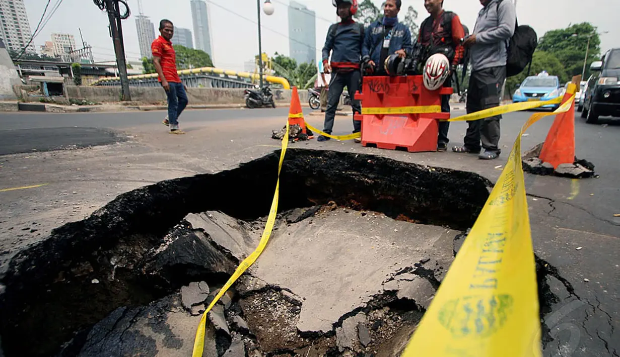 Penyebab amblesnya jalan tersebut diperkirakan karena pipa air yang bocor, sehingga tanah menjadi tergerus dan menyebabkan rongga. Foto diambil pada Kamis (6/11/2014). (Liputan6.com/Johan Tallo) 